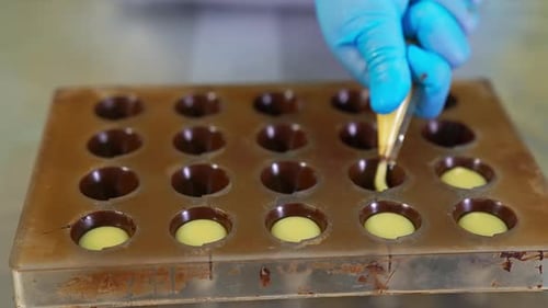 Handmade manufacturing of chocolate. Filling the molds with creamy stuffing from pastry bag.