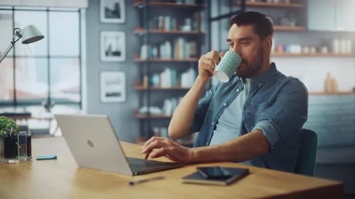 Man Working on Laptop and Drinking Coffee