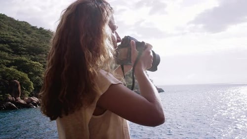 Photographe de voyage touristique avec appareil photo reflex numérique, photographiant au lever du soleil depuis le balcon d'une cabane de plage et...