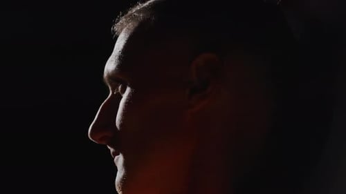 Closeup Of Strong Face Of Athletic Man In Sportive Area Profile Portrait In Contour Light In Dark