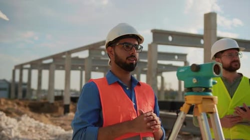 Mann mit Brille im Gespräch mit Ingenieuren über ein Bauprojekt nutzen optische Pegel im Stehen