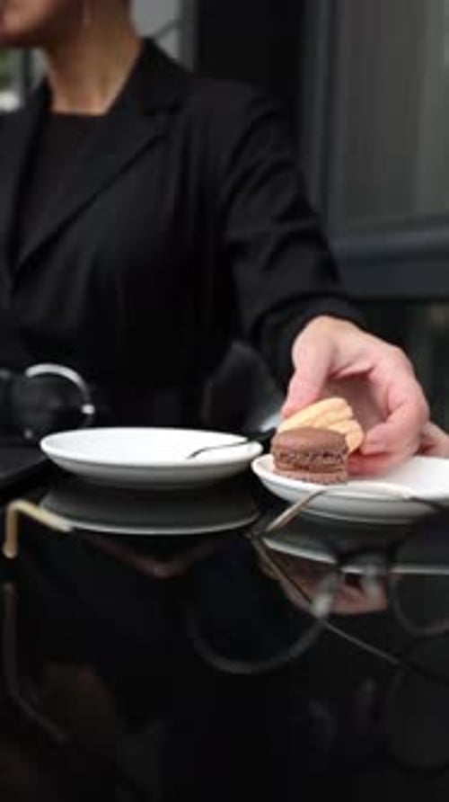 Woman Eats Macaron at Cafe Table