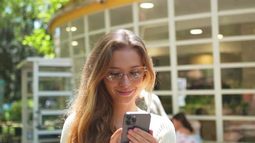 Woman Uses Smartphone in Sunny Urban Setting