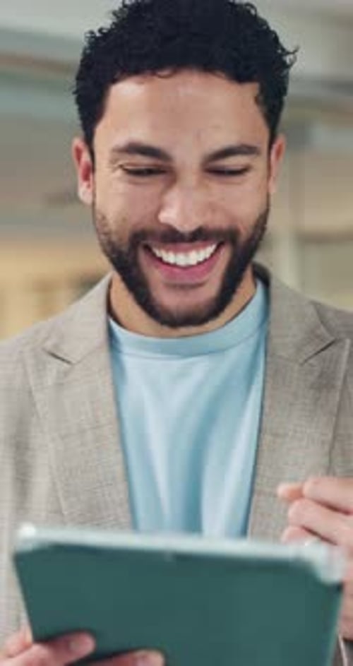Man Smiles Looking at Tablet Device at Workplace
