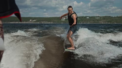 A Young Attractive Man is Learning to Wakesurf Behind a Boat Fun Water Activity During Hot Summer