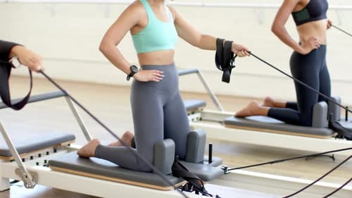 femme utilisant un réformateur Pilates, femme caucasienne ajustant les bretelles