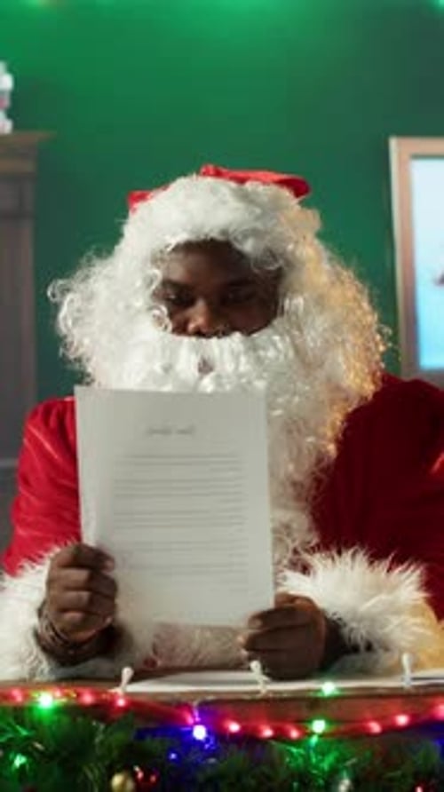 Vertical Video Santa Claus Reads a Christmas Letter By the Fireplace in His Workshop
