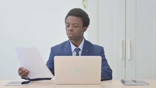 Young Adult Reviews Documents at Desk