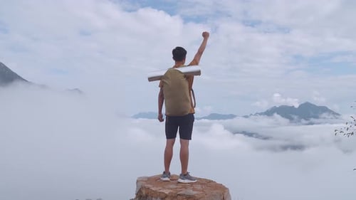 Hiker Male Standing On The Rock And Raising His Hand Celebrating Reaching Up Top Of Foggy Mountain