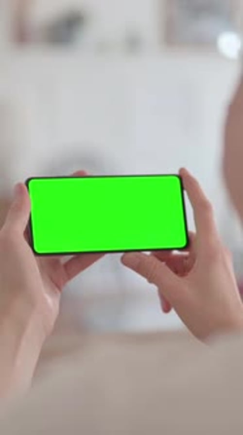 Rear View of Woman Holding Smartphone with Green Screen, vertical video