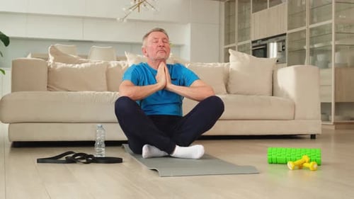 Senior Man Meditating on Yoga Mat Indoors