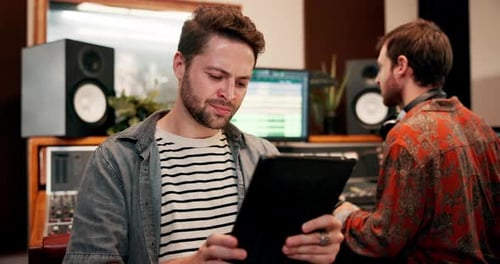 Man, producer and browsing tablet in music studio for online or internet research for lyrics