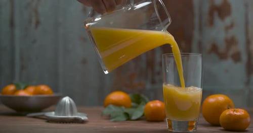 Fresh Orange Juice Poured Into Glass on Wooden Table