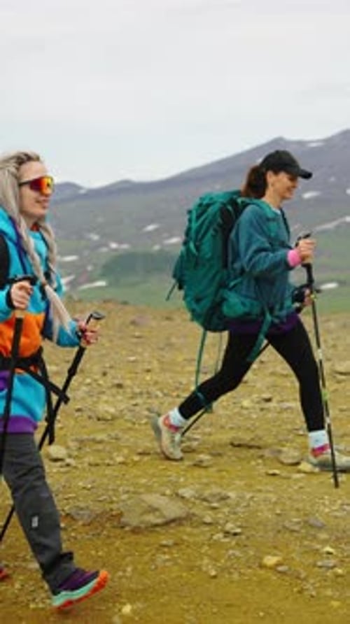 Deux randonneurs aventureux avec des sacs à dos et des bâtons de randonnée traversant un sentier de montagne rocheuse à