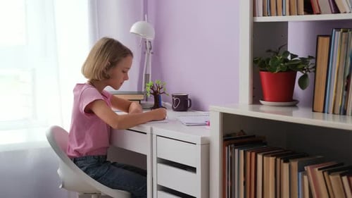 Little Girl Writing in Her Notebook at Home