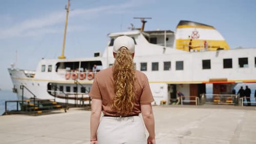 Young Woman Walks to Ferry Boat at Sunny Seaside Port Holds Bag Approaches Ship Ready for Water