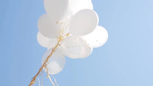 White Balloons Floating Against Blue Sky Background