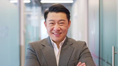 Businessman Smiling With Arms Crossed In Office Setting