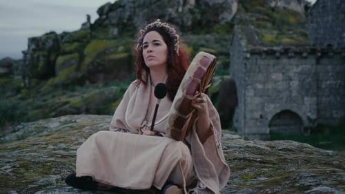 spiritual woman playing a shamanic drum in a beautiful medieval village track in shot
