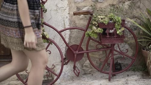 Static Video of a White Woman Crossing Next to an Iron Bicycle with Plants