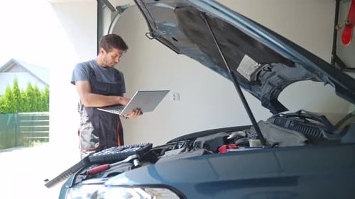 Automechaniker verwendet Laptop für die Fahrzeugdiagnose in der Garage