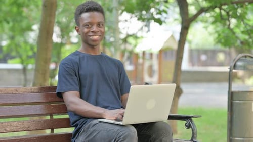 Young Adult Using Laptop on Park Bench