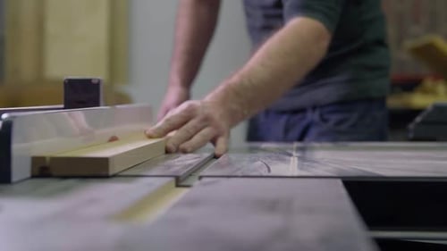 Man cuts wood on a table saw in his shop