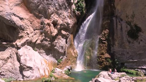 People take a bath under a waterfall during summer aerial drone view