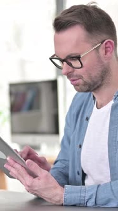 Man Uses Tablet at Desk in Bright Home