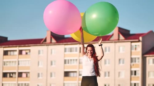 Happy Girl with Big with Colorful Balloons Posing on the Background of City Houses
