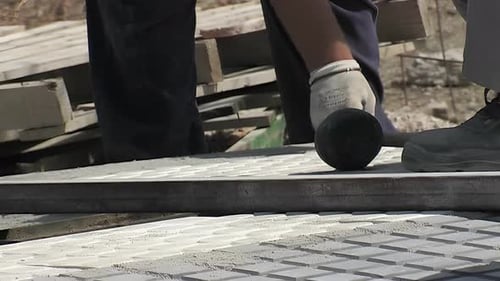Construction Worker Leveling Gray Tiles with Tool