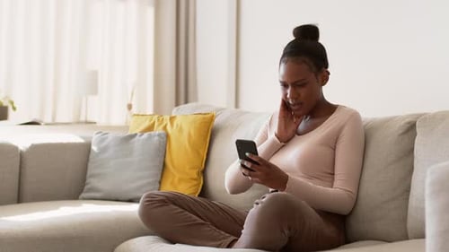 Worried Woman Using Smartphone on Couch at Home