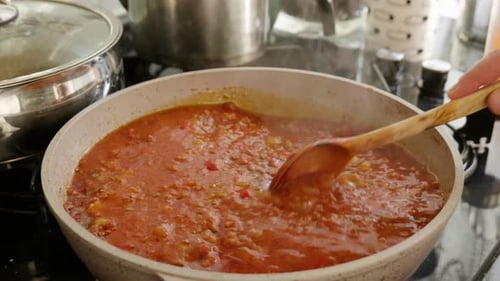 Bolognese Sauce Stirred with Wooden Spoon in Pan
