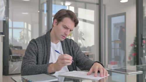 Young Man Working on Documents in Office