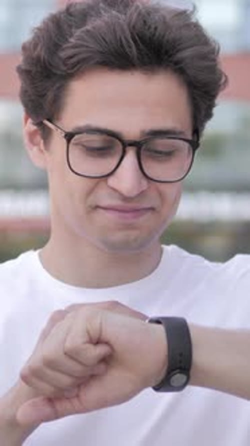 Young Man Checks Smartwatch in Urban Setting