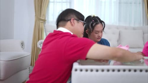 Three siblings save money by putting it in a piggy bank