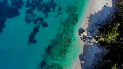 Farbenfrohe Küste mit Sandstrand und Klippen, umspült von azurblauem, sauberem Meerwasser an der Mittelmeerküste