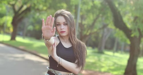 Young attractive woman standing at park raising arm with hand signalling to STOP