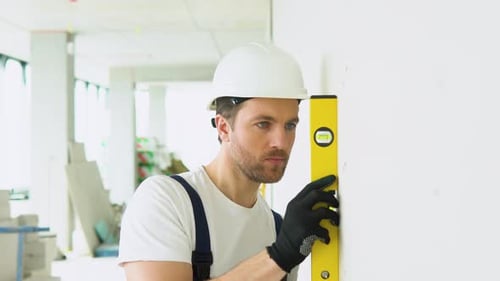 Construction Worker Uses Level on a Wall