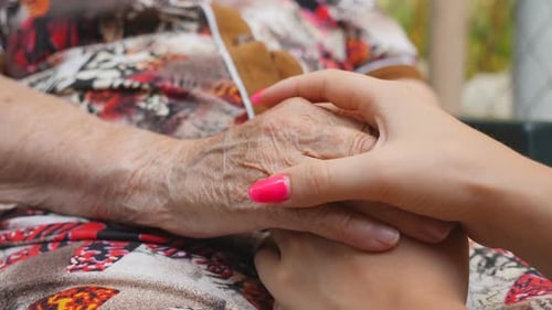 Young Adult Gently Holding Senior's Hand
