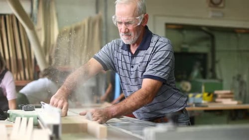 Senior Man Using a Table Saw in Workshop