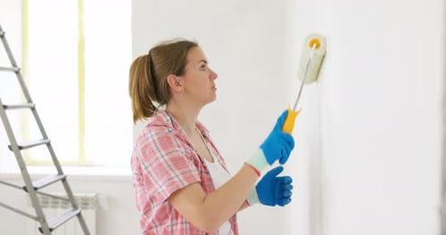 Woman Painting Wall with Roller Inside