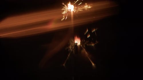 Two Sparklers Burning Vertically With Blurry Light Effects