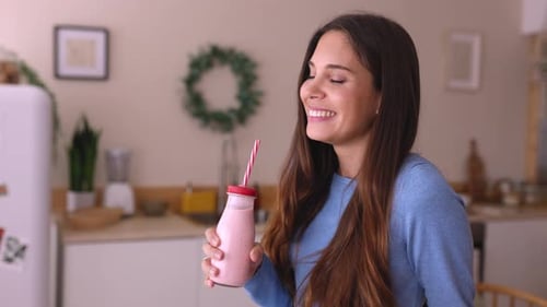 Young Woman Drinking Pink Smoothie in Kitchen