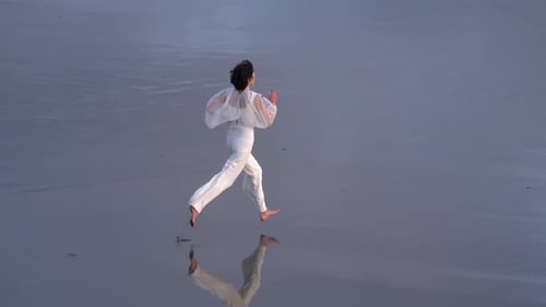 Adult Girl Running On The Ocean Shore Going To The Beach. aerial, tracking shot