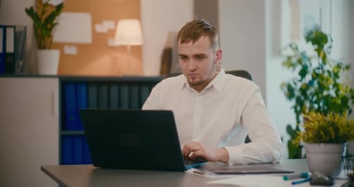 Businessman Using Laptop at Desk in Office