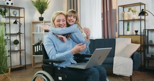 Happy Woman in Wheelchair Hugged by Her Daughter