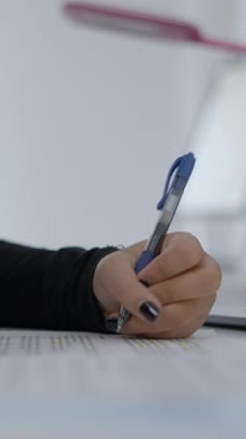 Close Up Shot of an Unrecognizable Young Girl's Hands Who is Sitting at a Desk and Writing in Her