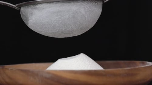 Flour Sifting through in Slow Motion with a black background 100 fps close