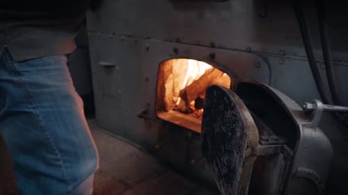 Adult Burns Wood In Industrial Metal Oven